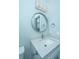 This bathroom features a round mirror, white vanity, and satin nickel hardware at 2501 Myrtle St, Edisto Beach, SC 29438