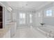Elegant bathroom featuring a soaking tub, glass-enclosed shower, marble counters and tile flooring, and natural light at 2522 Daniel Island Dr, Daniel Island, SC 29492