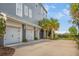 Three car garage with a driveway, palm trees and blue siding on a sunny day at 2522 Waverly St, Charleston, SC 29492