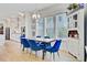 Bright dining room with a modern chandelier, large windows and blue velvet chairs around a wood table at 2557 Hatch Dr, Johns Island, SC 29455
