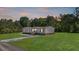 Charming single-story home with well-manicured lawn, gray siding, and surrounded by lush trees at sunset at 314 Hickory Nut Way, Cross, SC 29436