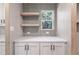 Close-up of a kitchen nook featuring open shelving, white cabinets, and a window with a view of the trees at 314 Hickory Nut Way, Cross, SC 29436