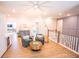 Open living area with hardwood floors, ceiling fan, neon sign, and railing overlooking downstairs at 3688 Goodwater St, Mount Pleasant, SC 29466