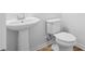 Cozy half bath with a pedestal sink and toilet, perfect for guests. White paint and wood-look floors at 403 Cadbury Loop, Summerville, SC 29486