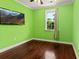 Bright green bedroom with hardwood floors, a window with curtains, and a wall-mounted television at 4637 Bonnie Marie Way, North Charleston, SC 29405