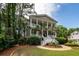 Elegant two-story home features a stunning porch, lush greenery, and mature palm trees at 4991 Sound View Dr, Mount Pleasant, SC 29466