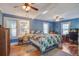 Cozy blue bedroom features wood floors, ceiling fans, and a comfortable bed with patterned quilt at 5615 Highway 165, Ravenel, SC 29470