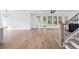 Open living area featuring light wood-look floors, white walls, staircase, and access to a backyard with natural light at 5655 Captain Kidd Rd, Hollywood, SC 29449
