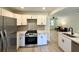 Modern kitchen with stainless steel appliances, white cabinets, and a view into the living room at 6086 Chisolm Rd, Johns Island, SC 29455