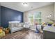 Bedroom featuring a blue accent wall, wood-look floors, and natural light from the large window at 7999 Vermont Rd, North Charleston, SC 29418