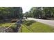 A tranquil street view with green lawns, trees, and distant houses behind a chain link fence at 107 Kelly St, Walterboro, SC 29488