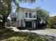 Charming two-story home with a dark garage door, a small balcony, and a gravel driveway surrounded by mature trees at 124 Charleston Blvd, Isle of Palms, SC 29451