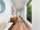 Sunlit hallway featuring hardwood floors, modern art, and large windows overlooking lush greenery at 124 Charleston Blvd, Isle of Palms, SC 29451