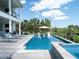 A refreshing swimming pool with an umbrella, accompanied by relaxing lounge chairs, surrounded by lush greenery and a bright sky at 124 Charleston Blvd, Isle of Palms, SC 29451
