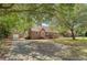 Full front exterior of brick home with a detached garage, driveway and mature tree coverage at 13 Charlestowne Rd Rd, Charleston, SC 29407