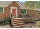 Close-up of the house entrance featuring a red door, brick steps and a small seating area at 13 Charlestowne Rd Rd, Charleston, SC 29407