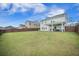 Expansive backyard with lush green grass, a dark wooden fence, and a covered patio at 134 Lucca Dr, Summerville, SC 29486