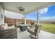 Relaxing covered patio features comfortable seating, a ceiling fan, and a serene view of the fenced backyard and lake at 134 Lucca Dr, Summerville, SC 29486