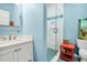 Light blue bathroom features a white vanity, sink, and glass-enclosed shower at 1404 Palmetto Blvd, Edisto Beach, SC 29438