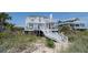 Stunning beachfront house with balconies and stairs, set amidst lush greenery and sand dunes at 1404 Palmetto Blvd, Edisto Beach, SC 29438