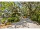 Exterior view of the home shows lush landscaping, a gravel driveway, and a detached garage at 2187 Saint James Dr, Charleston, SC 29412