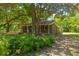 Quaint brick home with a covered porch, nestled under mature trees and lush landscaping at 2234 River Rd, Johns Island, SC 29455