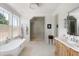 Bright bathroom features a soaking tub under a window, a glass shower, and a wooden vanity at 2538 Helmsman Rd, Johns Island, SC 29455