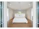 Elegant bedroom with a plush white bed, stylish paneling, and ample natural light from large windows at 2538 Helmsman Rd, Johns Island, SC 29455