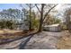 View of the home and a detached garage with a gravel driveway, complemented by mature trees at 301 Beaufort St, Summerville, SC 29483