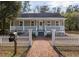 Charming cottage with a brick walkway, inviting front porch, white picket fence, and manicured landscaping at 301 Beaufort St, Summerville, SC 29483