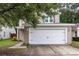 Attached two-car garage with a white door, complemented by light beige siding and mature landscaping at 3844 Annapolis Way, Ladson, SC 29456