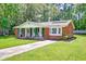 Charming brick home featuring a well-manicured lawn, inviting front porch, and vibrant green shutters at 403 Forest Cir, Summerville, SC 29483