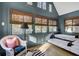 Comfortable bedroom with a trundle bed, white wicker chair, warm lighting, and natural light from multiple windows at 418 W Carolina Ave, Summerville, SC 29483