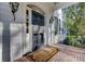 Inviting front porch with brick flooring leading to a black front door with glass panels and stylish sconces at 418 W Carolina Ave, Summerville, SC 29483