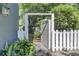Picturesque garden entryway with a white picket fence, stone path, and lush greenery at 418 W Carolina Ave, Summerville, SC 29483