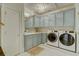Well-equipped laundry room with custom light blue cabinets, modern washer, and a dryer at 418 W Carolina Ave, Summerville, SC 29483