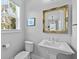 Stylish powder room includes a decorative mirror, pedestal sink, and natural light from the window at 539 Cooper Village Ln, Mount Pleasant, SC 29464