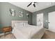 This bedroom features neutral decor, wall art, ceiling fan, and an ensuite bathroom for a calming retreat at 619 Trio Ln, Summerville, SC 29486
