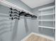 Bright walk-in closet with white shelving, rack and space saving hanger organizer on light blue walls with wood-look floor at 710 W Harrison Rd, Charleston, SC 29407