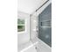 Modern bathroom featuring shiplap walls, a glass shower with blue tiling, and a bright window at 81 Avondale Ave, Charleston, SC 29407