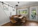 The dining room features a wooden table and six chairs with a sliding barn door and natural light at 8487 Parkers Ferry Rd, Adams Run, SC 29426