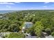 An aerial shot reveals a charming light blue home nestled among lush trees, near the ocean at 912 Cheehaw St, Edisto Island, SC 29438