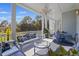 Covered porch with designer furniture, a chandelier, and views of serene landscape for relaxation and entertaining at 912 Cheehaw St, Edisto Island, SC 29438