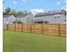A fenced back yard with green grass abuts neighboring two-story homes under a partly cloudy sky at 1441 Arabella St, Charleston, SC 29414