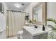 Bright bathroom with a white vanity, wood-trimmed mirror and decorative shelving and stylish shower curtain at 1705 Sulgrave Rd, Charleston, SC 29414