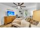 Well-lit bedroom with ceiling fan, wood floors, side table and large dresser with television at 1705 Sulgrave Rd, Charleston, SC 29414