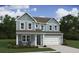 Charming two-story home with a light blue exterior, a front porch, and a two-car garage, surrounded by a lush green lawn at 2038 Mcguire Ln # 010, Hollywood, SC 29449