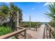 Wooden boardwalk with showers and beach access amidst lush greenery and palm trees at 208 Sea Cloud Cir, Edisto Island, SC 29438