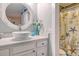 Bathroom featuring a seashell shower curtain, round mirror, and vessel sink on a white vanity at 220 E Arctic Ave, Folly Beach, SC 29439