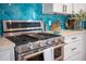 Close-up of a modern range with stainless steel appliances, tile backsplash, and white cabinetry at 220 E Arctic Ave, Folly Beach, SC 29439